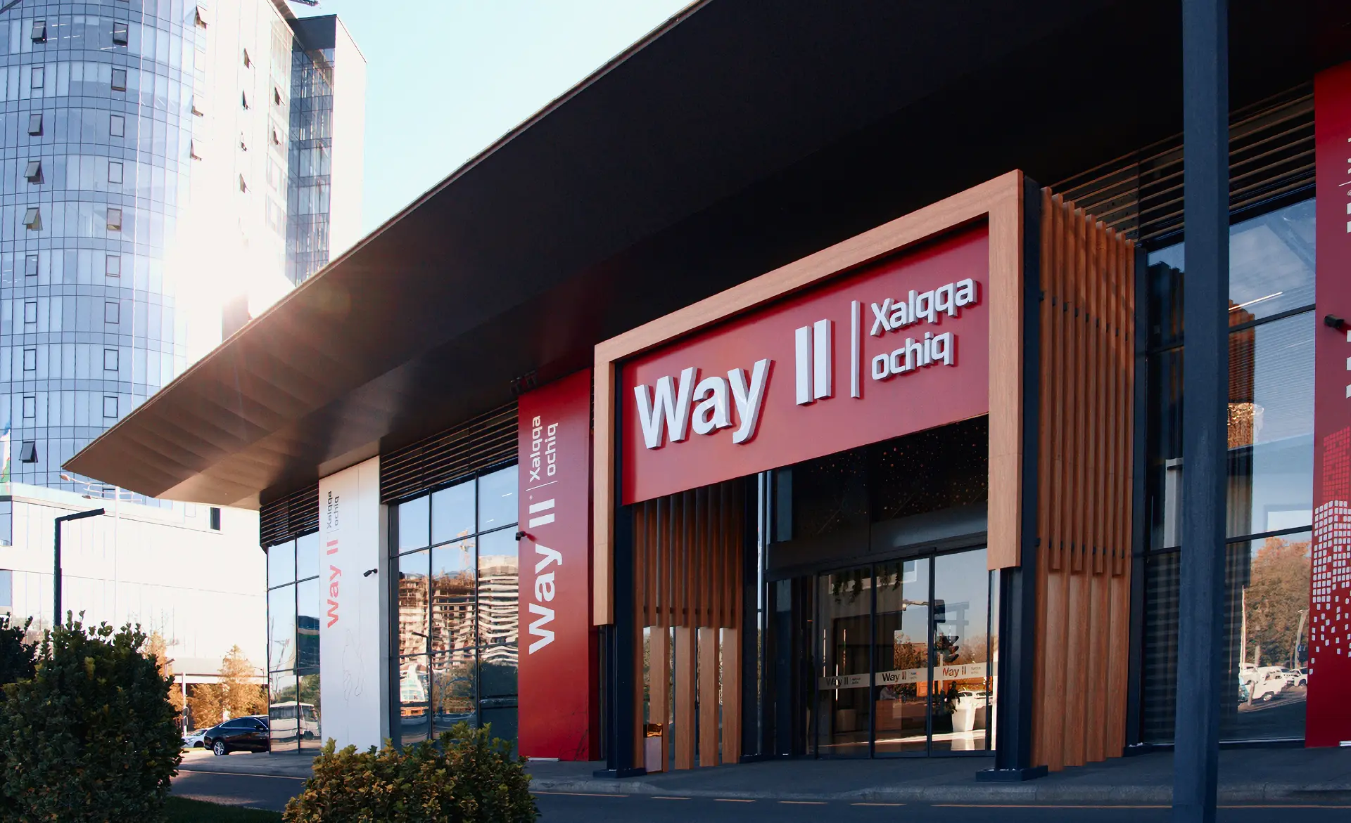 Way II bank branch exterior with red branding and modern glass facade in an urban setting.